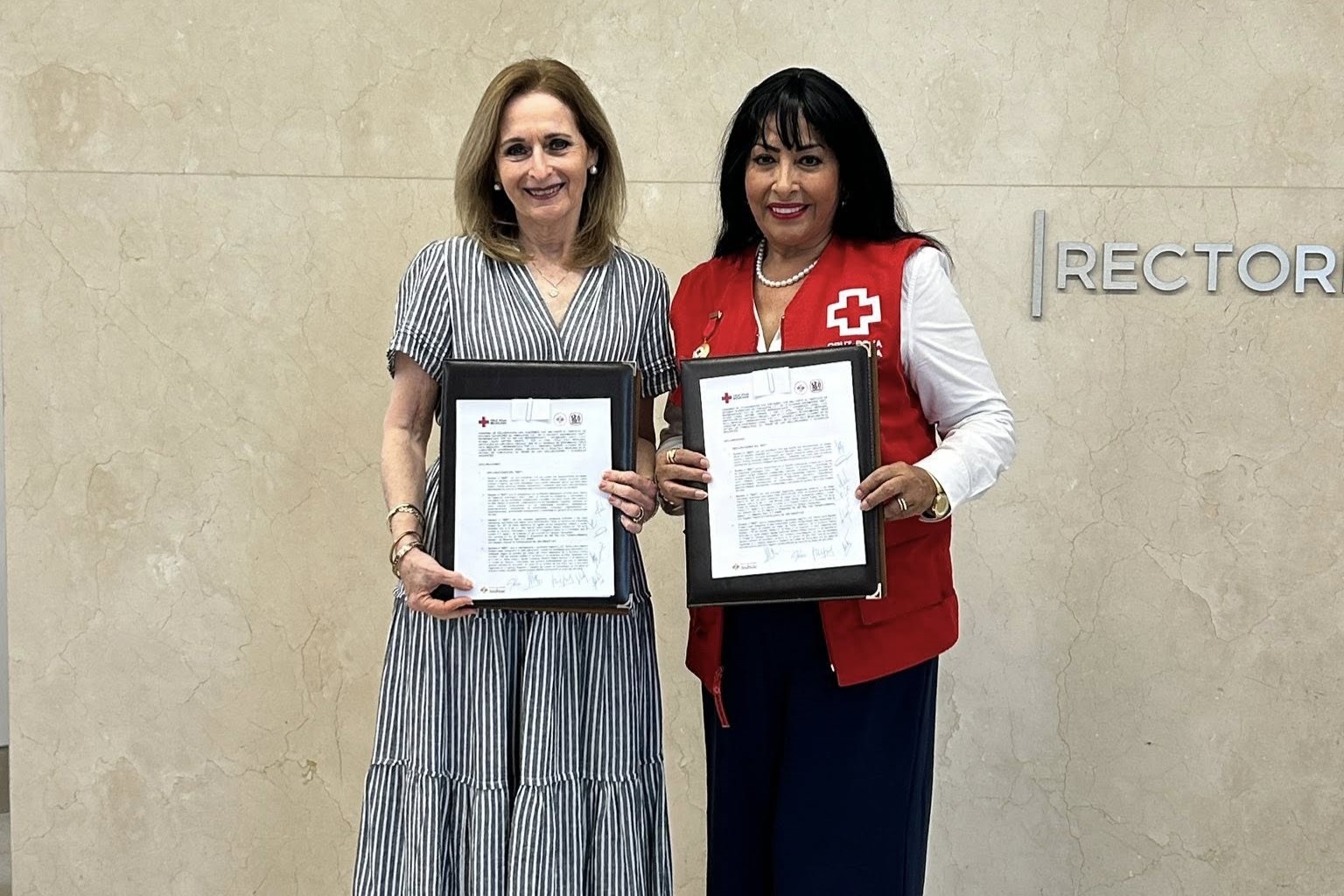 La Rectora y la Presidenta de la Cruz Roja sostienen sus respectivos convenios.