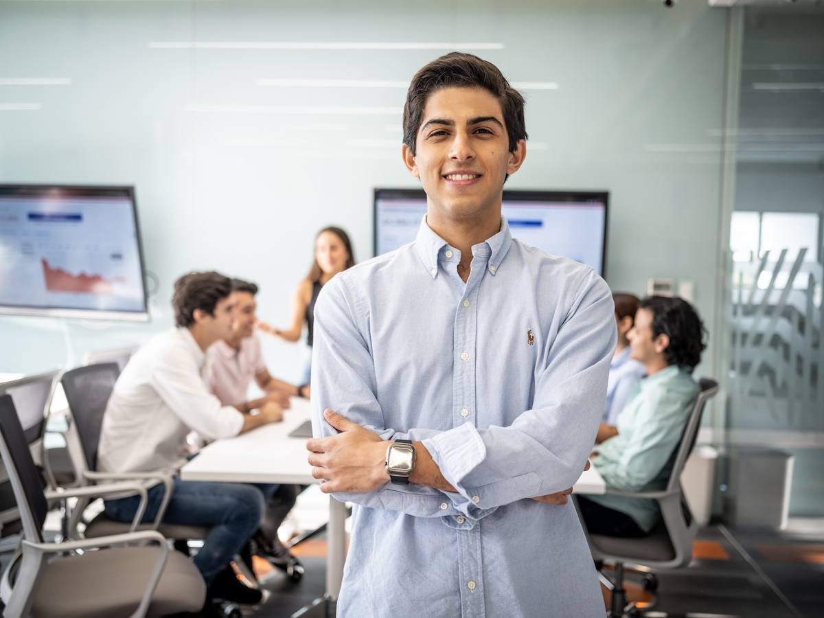 Estudiante de Relaciones Internacionales posando con seguridad frente a un equipo en sesión de análisis, con gráficas proyectadas al fondo, reflejando liderazgo, pensamiento estratégico y enfoque global.